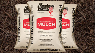 Three bags of Meadows Farm shredded hardwood mulch, each 3 cubic feet, on loose mulch ground.